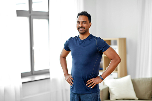 sport and healthy lifestyle concept - smiling indian man with fitness tracker at home