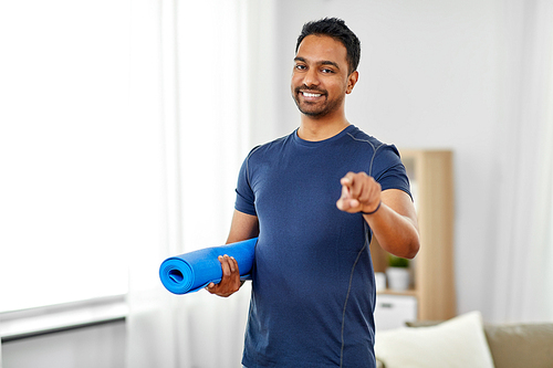 fitness, sport and healthy lifestyle concept - smiling indian man with exercise mat pointing to you at home