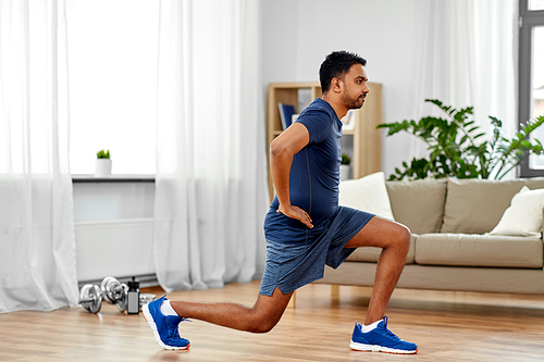 fitness, sport and healthy lifestyle concept - indian man exercising and doing lunge at home