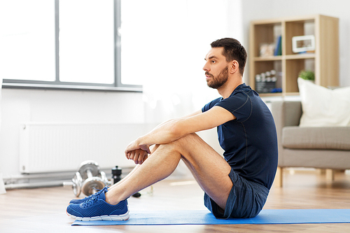 sport, fitness and healthy lifestyle concept - man resting on exercise mat at home