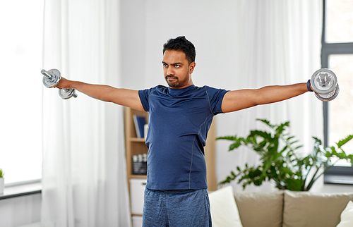 fitness, sport, weightlifting and bodybuilding concept - indian man exercising with dumbbells at home