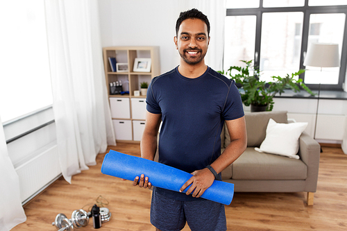 fitness, sport and healthy lifestyle concept - smiling indian man with exercise mat at home