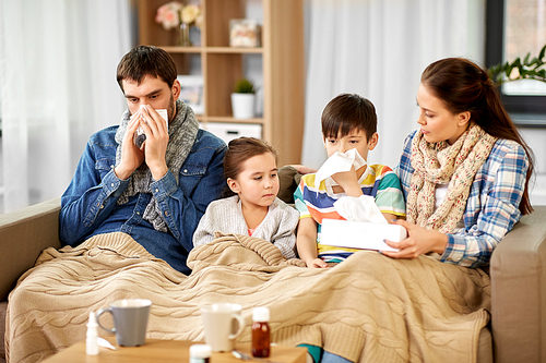 family, health problem and people concept - ill father, mother, daughter and son blowing nose at home
