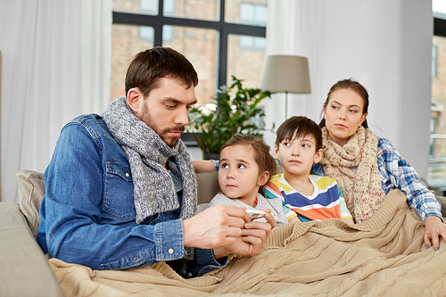 family, health and people concept - father with thermometer, mother and ill children having fever at home