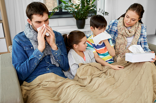 family, health problem and people concept - ill father, mother, daughter and son blowing nose at home