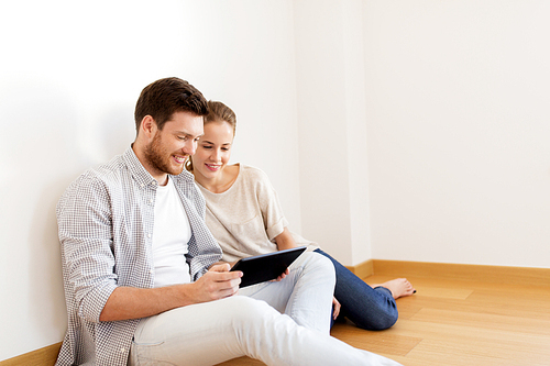 mortgage, people and real estate concept - happy couple with tablet pc computer at empty room of new home