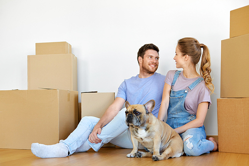 mortgage, people and real estate concept - happy couple with boxes and french bulldog dog moving to new home