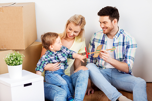 mortgage, people, family and real estate concept - happy mother, father and little son with cardboard boxes and toy airplane moving to new home