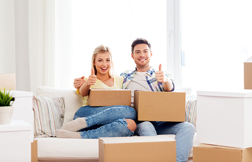 mortgage, moving and real estate concept - happy couple with boxes resting on sofa at new home