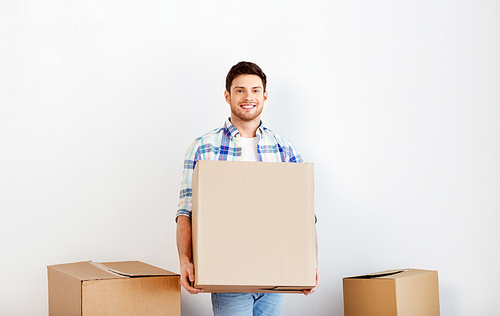 moving, people and real estate concept - happy man holding cardboard box at new home