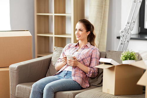 people, repair and real estate concept - smiling woman with stuff moving to new home and drinking coffee