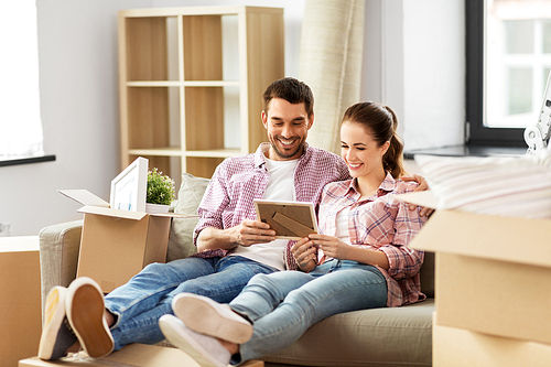 moving, people, repair and real estate concept - happy couple with photo frame and cardboard boxes sitting on sofa at new home