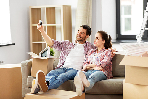 moving, repair and real estate concept - smiling couple taking selfie by smartphone at new home