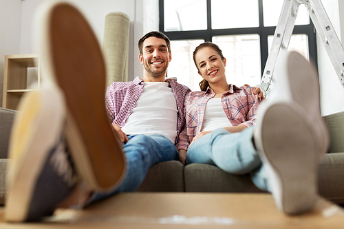 moving, people, repair and real estate concept - happy couple sitting on sofa at new home