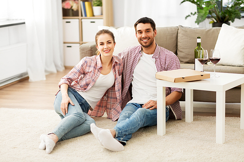 leisure, people and valentines day concept - happy couple with wine and takeaway pizza at home