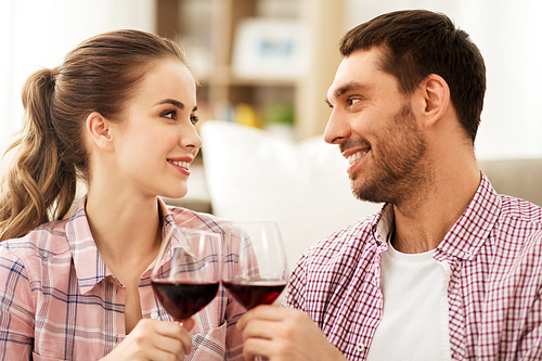 leisure, celebration and valentines day concept - happy couple drinking red wine at home