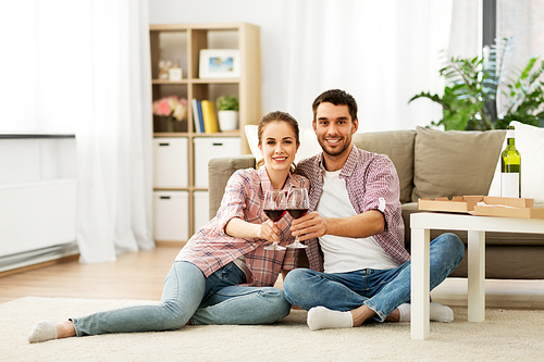 leisure, celebration and valentines day concept - happy couple drinking red wine at home