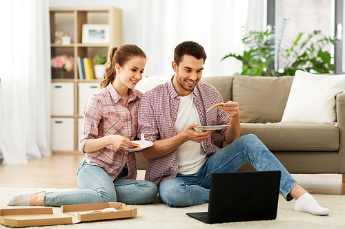 leisure, people and technology concept - happy couple with laptop computer eating takeaway pizza at home