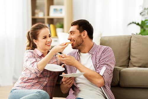 food, leisure and people concept - happy couple eating pizza at home