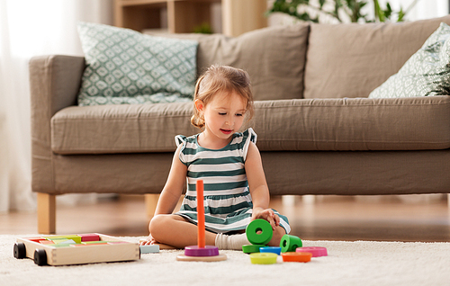 childhood and people concept - happy three years old baby girl playing with toy blocks at home