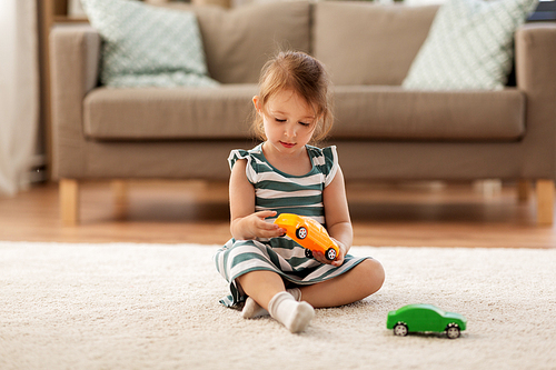 childhood and people concept - happy three years old baby girl playing with toy car at home