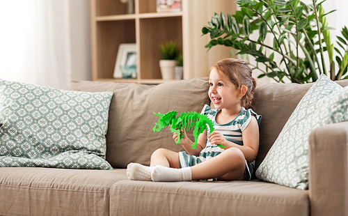 childhood and people concept - happy three years old baby girl playing with toy dinosaur skeleton at home