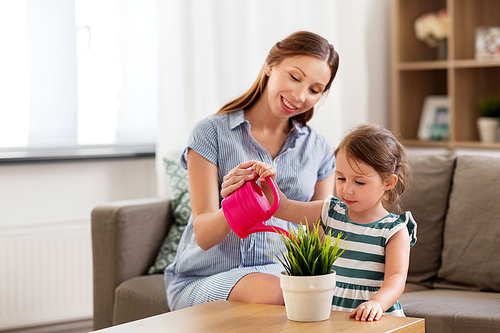 pregnancy, people and family concept - happy pregnant mother and little daughter with home plant and watering can