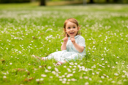 childhood, leisure and people concept - happy little baby girl at park in summer