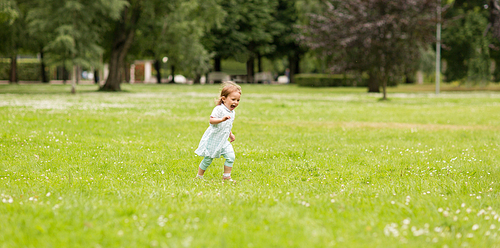 childhood, leisure and people concept - happy little baby girl running at park in summer