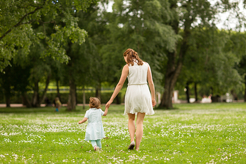 family, childhood and parenthood concept - mother with little baby daughter walking at summer park