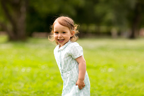 childhood, leisure and people concept - happy little baby girl at park in summer