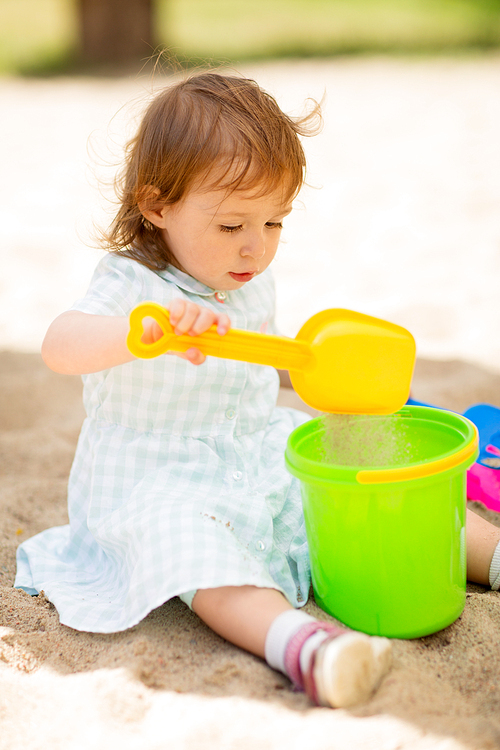 childhood, leisure and people concept - little baby girl plays with toys in sandbox