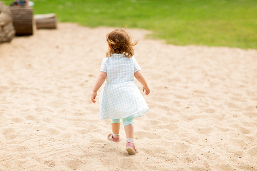 childhood, leisure and people concept - little baby girl at children's playground in summer