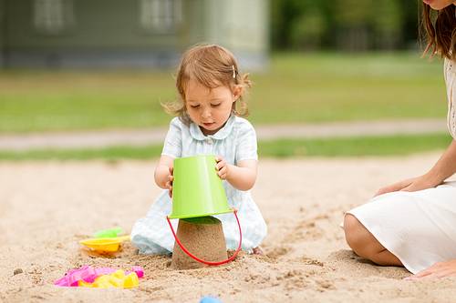 childhood, leisure and people concept - little baby girl plays with toys in sandbox