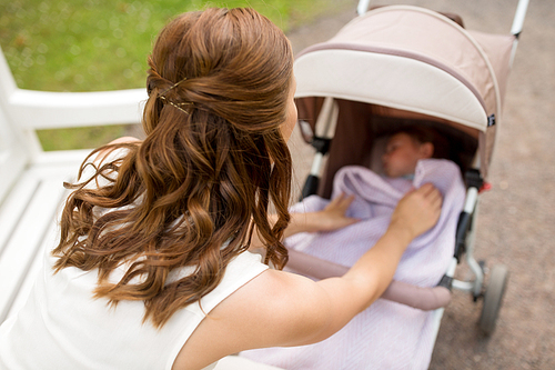 family, motherhood and people concept - close up of mother covering child in stroller with blanket at summer park