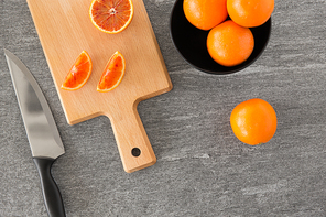 food, fruits and healthy eating concept - close up of blood oranges and kitchen knife on wooden cutting board