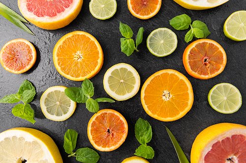 food and healthy eating concept - close up of grapefruit, orange, pomelo, lemon and lime slices on stone background