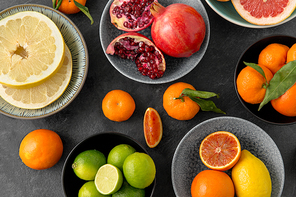 food, healthy eating and vegetarian concept - close up of citrus fruits in bowls on stone table