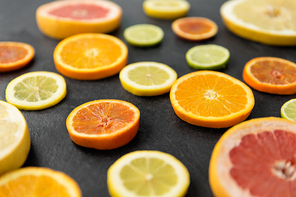 food and healthy eating concept - close up of grapefruit, orange, pomelo, lemon and lime slices on stone background