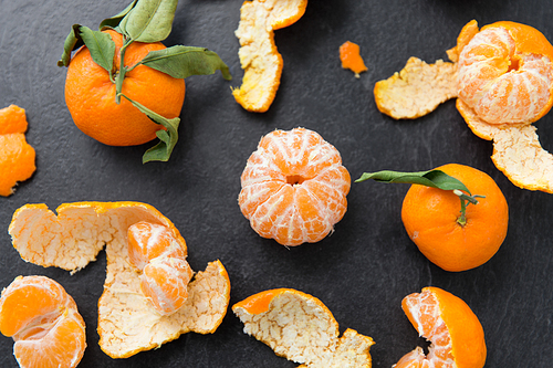 food, healthy eating and vegetarian concept - close up of peeled mandarins on slate table top