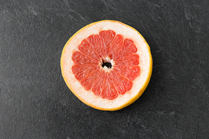 food, fruits and healthy eating concept - close up of fresh juicy grapefruit on slate background