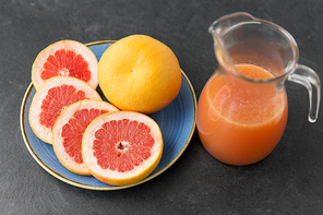 food , healthy eating and vegetarian concept - glass jug of fruit juice with grapefruits on plate