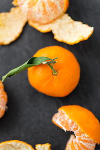 food, healthy eating and vegetarian concept - close up of peeled mandarins on slate table top