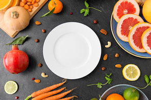 healthy eating, vegetarian food, diet and culinary concept - empty white plate and different vegetables and fruits on on slate table