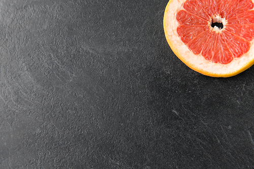 food, fruits and healthy eating concept - close up of fresh juicy grapefruit on slate background