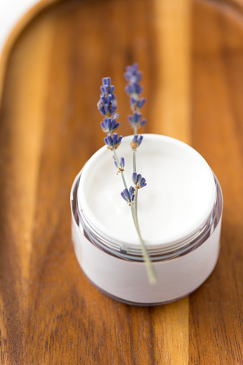 beauty and wellness concept - close up of lavender moisturizer on wooden tray