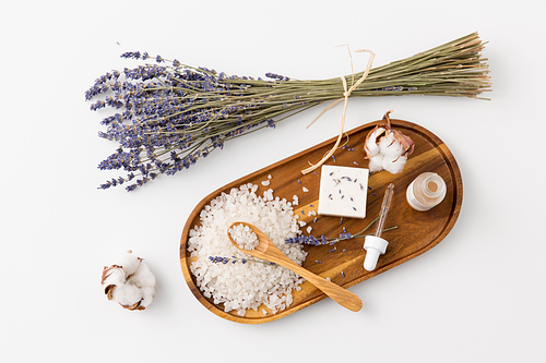 beauty and wellness concept - 씨솔트 with spoon, soap, serum with dropper, lavender and cotton flowers on wooden tray