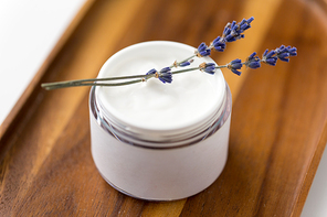 beauty and wellness concept - close up of lavender moisturizer on wooden tray