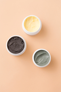beauty, spa and wellness concept - blue clay mask, body butter and therapeutic mud on beige background