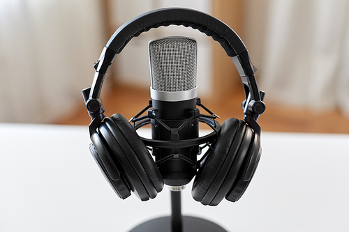 technology and audio equipment concept - headphones and microphone at home office or recording studio